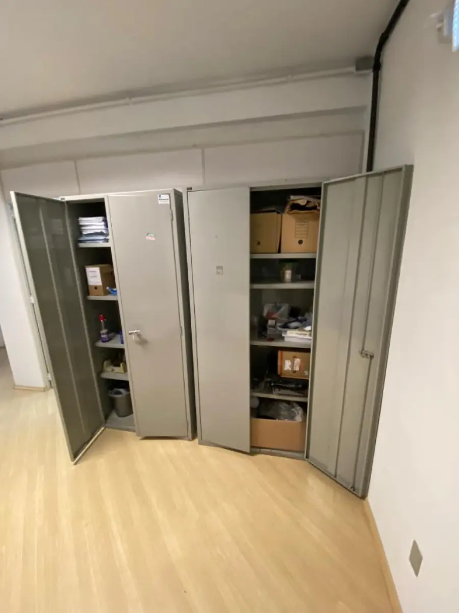 LOTE 018 - Uma mesa reta, uma mesa em L, uma mesa auxiliar, um arquivo em metal, um armário em madeira, uma estante com três nichos, dois armários de metal, materiais diversos de escritório e limpeza e dois telefones intelbrás.