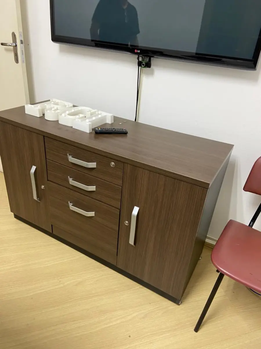 LOTE 013 - Mesa de reuniões, seis cadeiras de escritório pretas, uma cadeira vermelha, um Hack com gavetas e portas, um aparador baixo, uma televisão 49 polegadas LG e webcam.