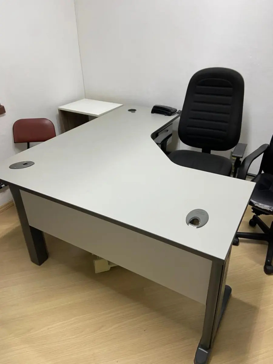 LOTE 016 - Uma mesa em L, um gaveteiro, uma mesa auxiliar, quatro cadeiras de escritório, duas poltronas de espera, um cabideiro, uma banqueta de plástico e um telefone Intelbras.