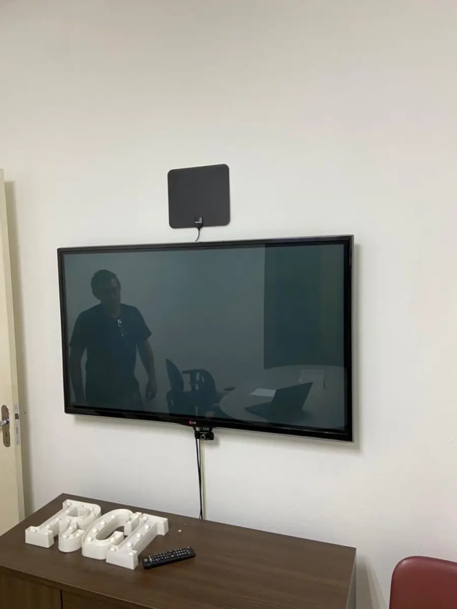 LOTE 013 - Mesa de reuniões, seis cadeiras de escritório pretas, uma cadeira vermelha, um Hack com gavetas e portas, um aparador baixo, uma televisão 49 polegadas LG e webcam.